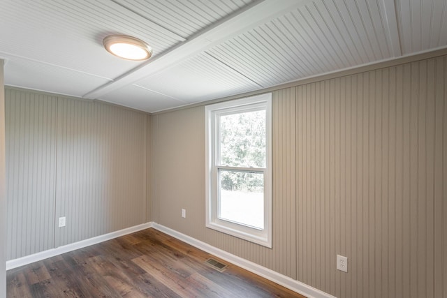 empty room featuring dark hardwood / wood-style flooring and beamed ceiling