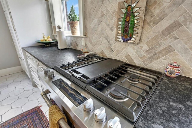 kitchen with light tile patterned floors, decorative backsplash, and cooktop