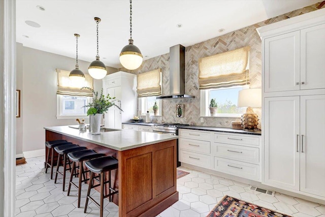 kitchen with white cabinetry, a center island, and wall chimney range hood