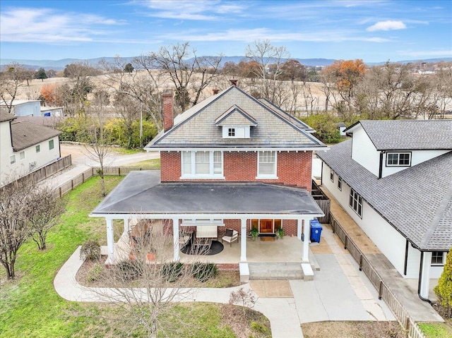 back of house with a mountain view and a lawn