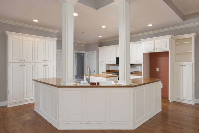 kitchen featuring a kitchen island with sink, white cabinets, and ornate columns