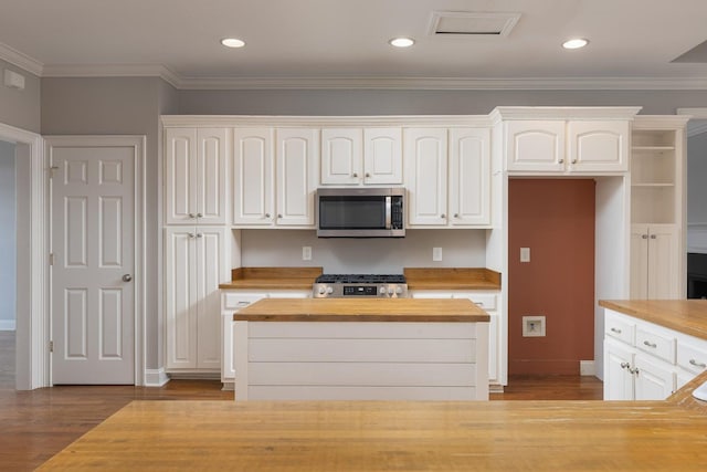 kitchen featuring crown molding, stove, white cabinets, and butcher block countertops