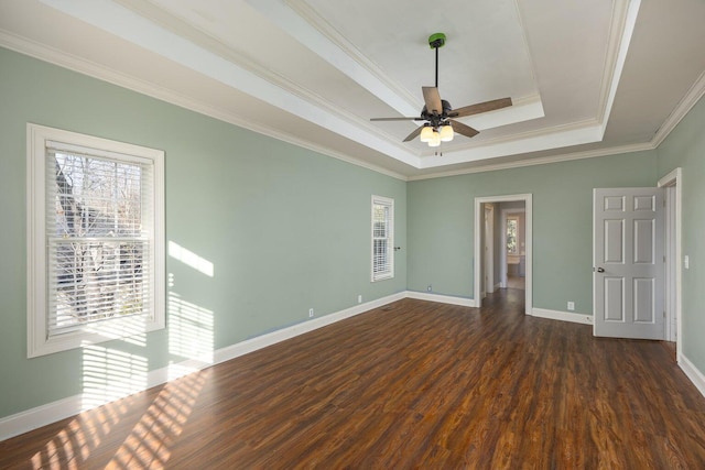 spare room featuring dark hardwood / wood-style flooring, a tray ceiling, ornamental molding, and ceiling fan