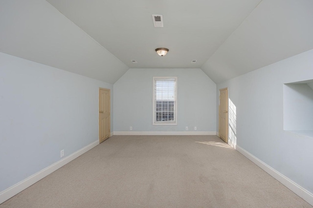 bonus room with vaulted ceiling and light carpet