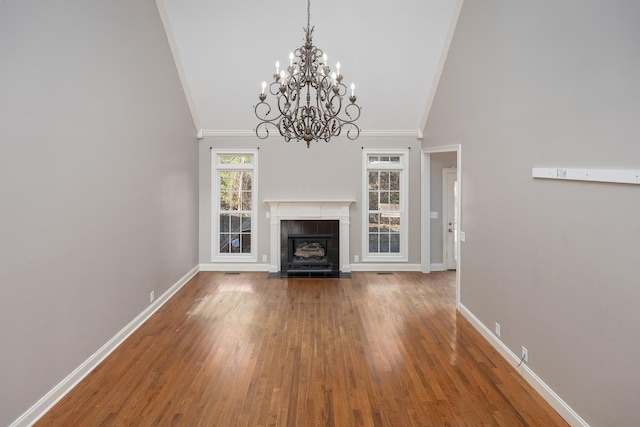 unfurnished living room with hardwood / wood-style floors, ornamental molding, a tile fireplace, and high vaulted ceiling