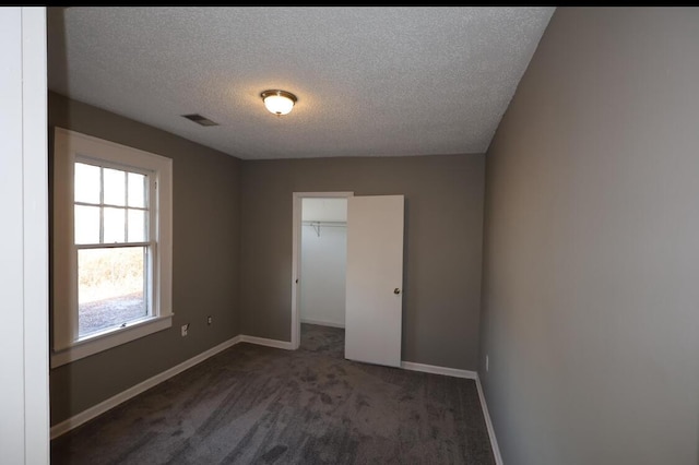 carpeted empty room with a textured ceiling