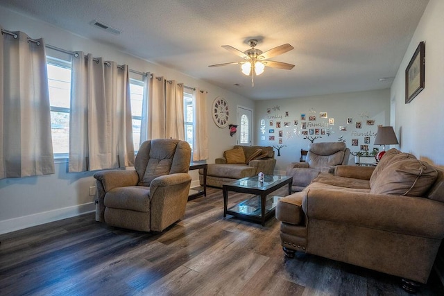 living room with dark wood-type flooring, ceiling fan, and a textured ceiling