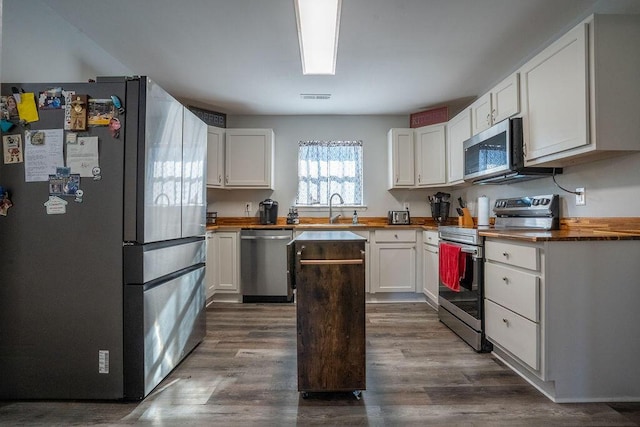 kitchen featuring butcher block countertops, sink, dark wood-type flooring, white cabinetry, and stainless steel appliances