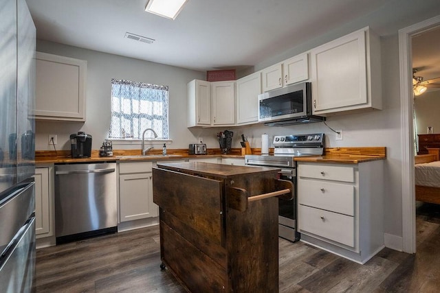 kitchen featuring stainless steel appliances, white cabinetry, sink, and dark hardwood / wood-style floors