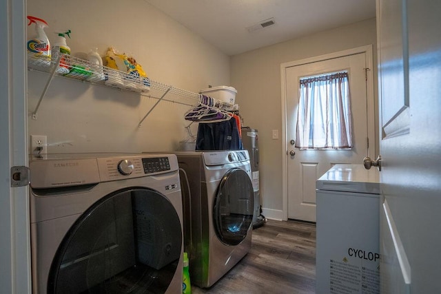 washroom featuring electric water heater, washing machine and dryer, and dark hardwood / wood-style floors