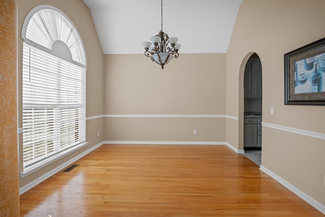 spare room with light wood-type flooring, lofted ceiling, and a chandelier