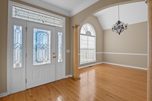 foyer entrance featuring light hardwood / wood-style floors, an inviting chandelier, decorative columns, and ornamental molding