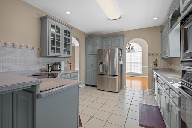 kitchen featuring gray cabinets, light tile patterned floors, stainless steel appliances, and backsplash