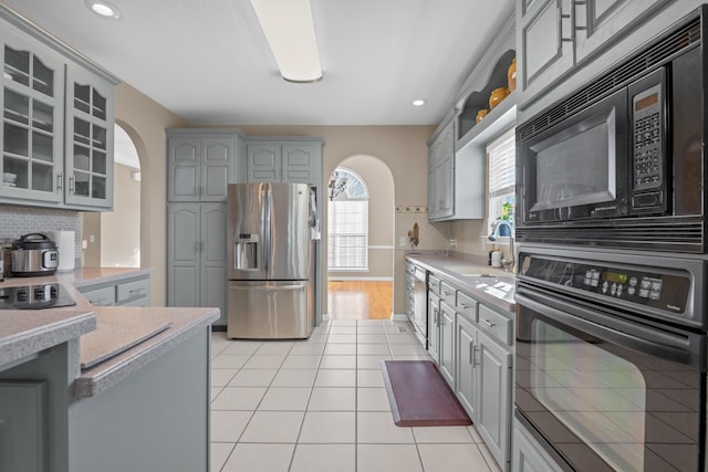 kitchen featuring gray cabinetry, black appliances, decorative backsplash, light tile patterned floors, and sink