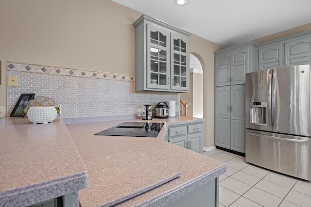 kitchen featuring gray cabinetry, light tile patterned flooring, black electric stovetop, and stainless steel fridge