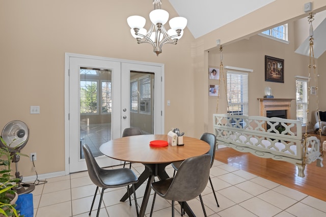 dining area with high vaulted ceiling, light tile patterned flooring, an inviting chandelier, and french doors