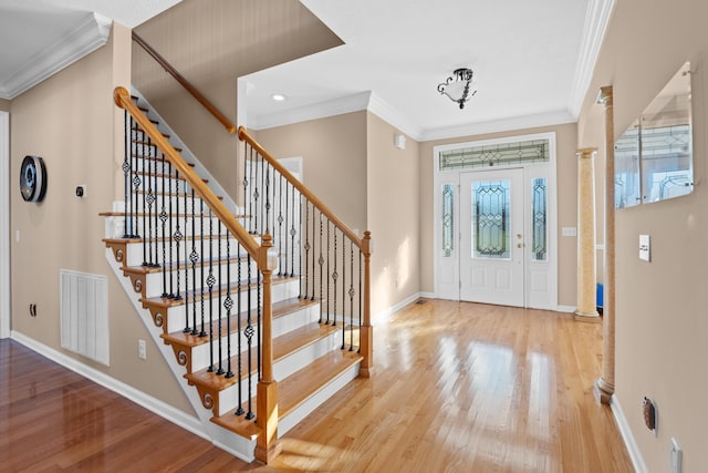 foyer featuring hardwood / wood-style floors, decorative columns, and ornamental molding