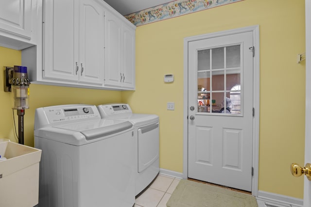 laundry area featuring cabinets, light tile patterned floors, washer and clothes dryer, and sink