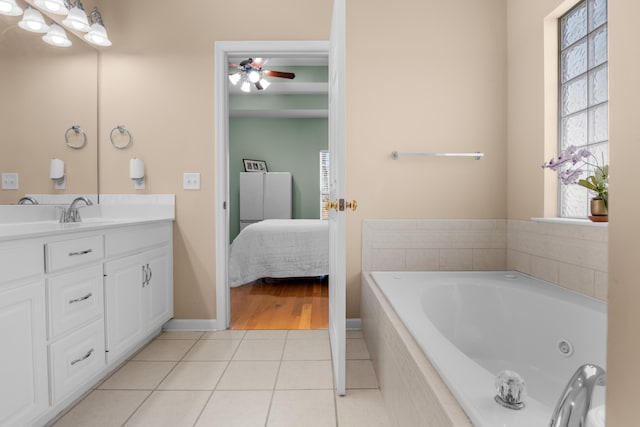 bathroom featuring ceiling fan, vanity, tile patterned flooring, and a relaxing tiled tub