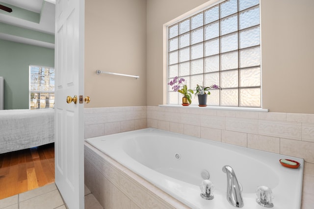 bathroom with a relaxing tiled tub and tile patterned floors