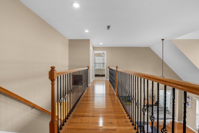 corridor with light hardwood / wood-style floors and vaulted ceiling