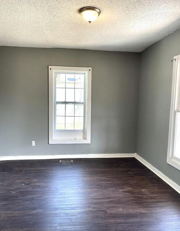 unfurnished room featuring dark wood-type flooring and a textured ceiling