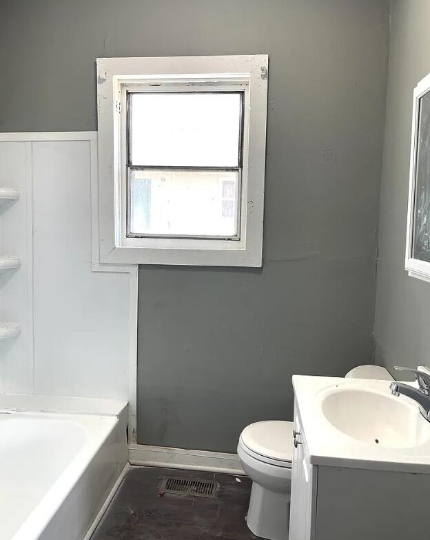 bathroom featuring hardwood / wood-style flooring, vanity, a washtub, and toilet