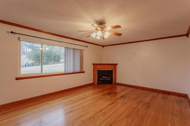 unfurnished living room with a fireplace, ornamental molding, ceiling fan, light hardwood / wood-style floors, and a textured ceiling