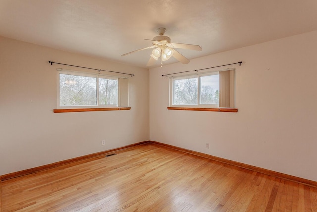 empty room featuring plenty of natural light, ceiling fan, and light wood-type flooring