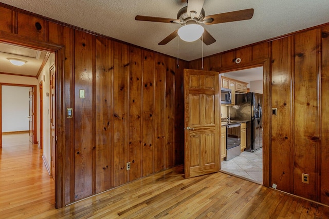 unfurnished room with crown molding, light hardwood / wood-style flooring, a textured ceiling, and wood walls