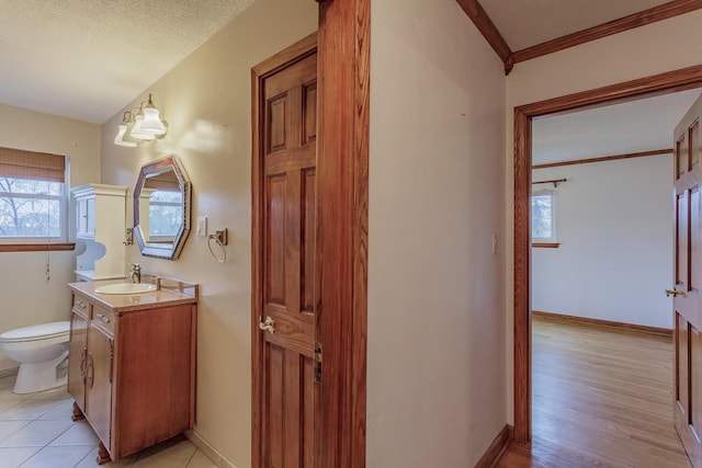 bathroom with hardwood / wood-style flooring, vanity, toilet, crown molding, and a textured ceiling