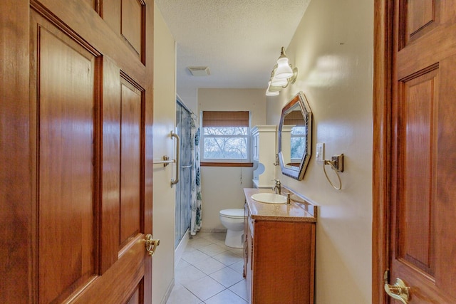 bathroom with toilet, a textured ceiling, vanity, a shower with door, and tile patterned flooring