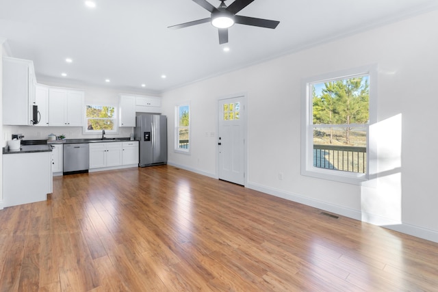 unfurnished living room featuring ceiling fan, ornamental molding, sink, and light hardwood / wood-style floors