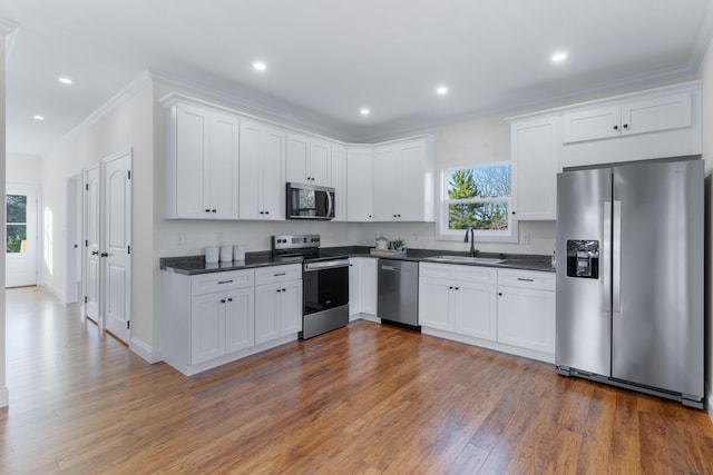 kitchen featuring hardwood / wood-style flooring, appliances with stainless steel finishes, sink, and white cabinets