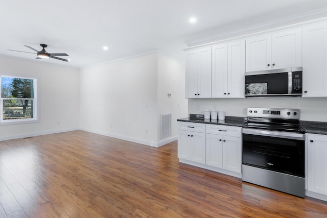 kitchen featuring stainless steel appliances, white cabinetry, dark hardwood / wood-style floors, and dark stone countertops