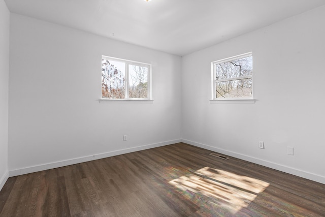 spare room with dark wood-type flooring and a wealth of natural light