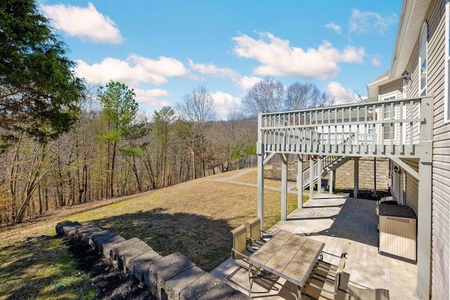 view of yard with a forest view, stairs, a deck, and a patio