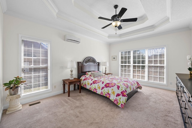 bedroom with light colored carpet, visible vents, multiple windows, a wall mounted air conditioner, and a raised ceiling