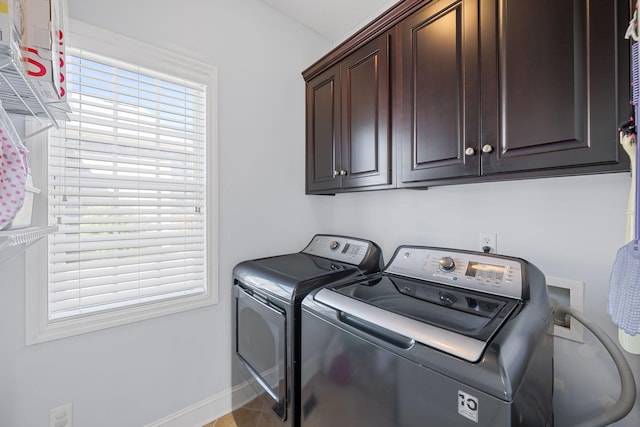 clothes washing area with cabinet space, baseboards, and washer and dryer