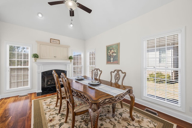 dining area featuring vaulted ceiling, plenty of natural light, a fireplace, and visible vents