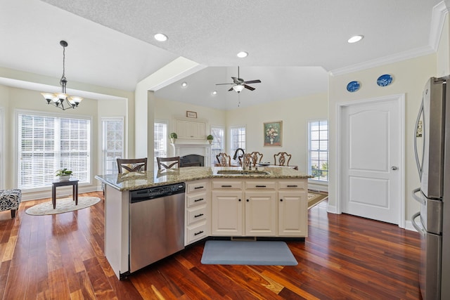 kitchen featuring light stone counters, stainless steel appliances, a fireplace, white cabinetry, and a sink