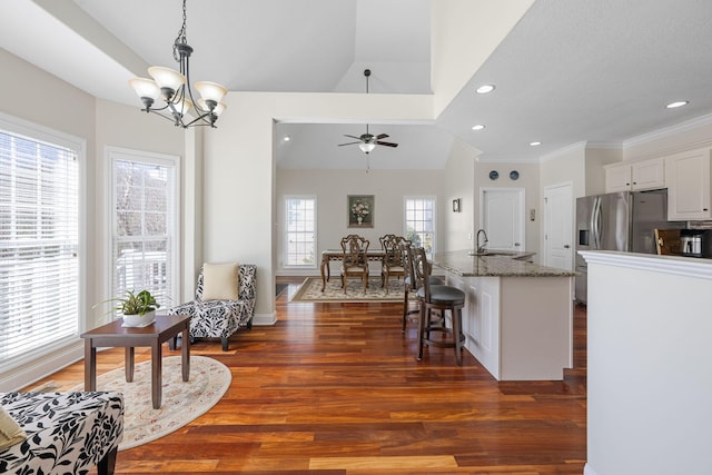 kitchen featuring a breakfast bar, dark wood-style flooring, a sink, and dark stone countertops