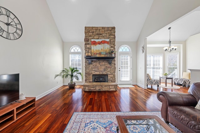 living area with hardwood / wood-style flooring, baseboards, high vaulted ceiling, and a stone fireplace