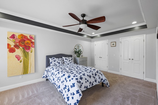 carpeted bedroom with multiple closets, recessed lighting, a raised ceiling, and baseboards