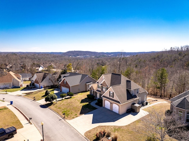 drone / aerial view featuring a wooded view and a residential view