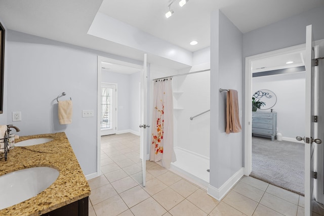 full bathroom with curtained shower, tile patterned flooring, baseboards, and a sink