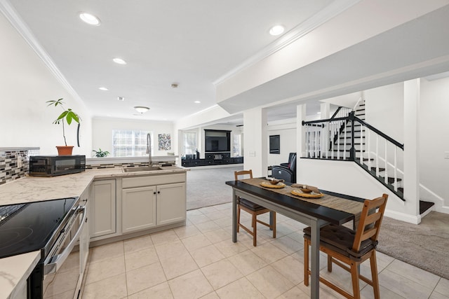 kitchen with light carpet, ornamental molding, open floor plan, and a sink