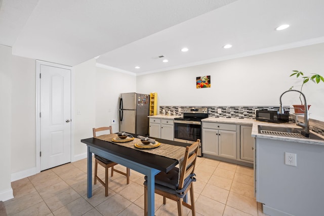 kitchen featuring tasteful backsplash, appliances with stainless steel finishes, ornamental molding, light countertops, and a sink