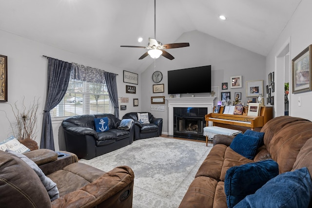 living room with ceiling fan, a tiled fireplace, vaulted ceiling, and hardwood / wood-style floors