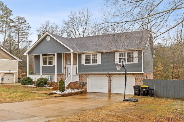 bi-level home with a garage, a front lawn, and covered porch